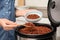 Woman putting delicious brown rice into bowl from multi cooker