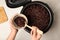 Woman putting delicious brown rice into bowl from multi cooker at table