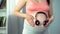 Woman putting earphones on her pregnant belly, enjoying favorite music with baby