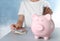 Woman putting Euro banknote into piggy bank at table, closeup. Money savings