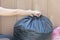 Woman putting garbage bag into trash can. Bind it to make it easy to move