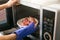 Woman putting grilled pork into microwave oven. inside view