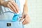 Woman putting hand sanitizer in purse on light background, closeup. Personal hygiene during COVID-19 pandemic