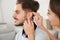 Woman putting hearing aid in man`s ear