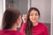 Woman putting make-up in the LED lighted mirror getting ready morning beauty routine applying mascara eye makeup. Asian