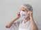 A woman putting on a medical mask with sign Stop Pandemia to avoid contagious viruses