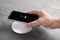 Woman putting mobile phone onto wireless charger at table, closeup