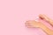 Woman putting moisturizer hands cream on a pink background