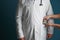 Woman putting money in pocket of doctor\'s coat on color background. Corruption concept