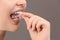 Woman putting occlusal splint in mouth on grey background, closeup