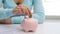 Woman putting one euro coin into piggy bank