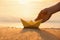 Woman putting origami boat on water surface near bank