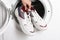 Woman putting pair of sport shoes into washing machine, closeup