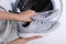 Woman putting pair of sport shoes into washing machine, closeup