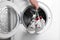 Woman putting pair of sport shoes into washing machine, closeup