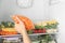 Woman putting plastic bag with carrot in refrigerator with frozen vegetables