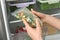 Woman putting plastic bag with vegetables in refrigerator, closeup