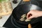 Woman putting raw gyoza on frying pan with hot oil, closeup