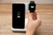 Woman putting smartwatch onto wireless charger at table, closeup. Modern workplace accessory