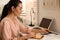 Woman putting smartwatch onto wireless charger at table. Modern workplace accessory