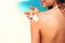 Woman putting sunblock lotion on shoulder before tanning during summer holiday on beach vacation resort.