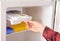 Woman putting tray with citrus fruits frozen in ice cubes into refrigerator