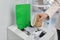 Woman putting used paper cup into trash bin in office, closeup. Waste recycling