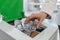 Woman putting used plastic bottle into trash bin in office, closeup. Waste recycling