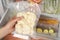 Woman putting vacuum bag with cauliflowers into fridge, closeup. Food storage