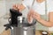 Woman putting vacuum packed meat into pot and using thermal immersion circulator, closeup. Sous vide cooking