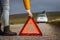 Woman putting warning triangle on road because car is broken