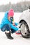 Woman putting winter tire chains car wheel