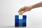 Woman putting wooden block to cubes on white background, closeup. Career promotion concept