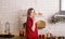 Woman in pyjamas smiling and calling to taste festive food. Cooking dinner at christmas eve in decorated kitchen. Home interior