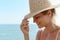 Woman radiates summer vibes wearing yellow striped bikini and a straw hat, enjoying her time on the sandy beach