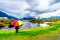 Woman with a rainbow colored Umbrella under dark rain clouds on a cold spring day at the lagoons of Pitt-Addington Marsh