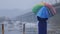 Woman with rainbow umbrella during snowfall