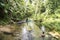 Woman in rainforest creek, man in canoe, West Papua