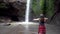 Woman raise hands standing near waterfall in Bali