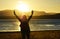 Woman raising hands worshiping praising praying God beautiful sunset