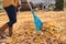 Woman raking leaves in vest and boots