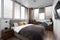 Woman reading book in a bedroom with bed and wooden wardrobe in modern apartment