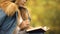 Woman reading book and drinking tea on backyard, enjoying fall weather, pleasure