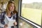 Woman reading book looking out train window