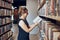 Woman reading book in public library. Teacher searching for literature for reading and learning. Woman standing among bookshelves