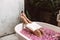 Woman reading book while relaxing in bath tub with flower petals