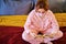 Woman is reading a book sitting on a red bed in quarantine. Girl in a makeshift protective mask isolated during coronavirus