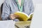 Woman reading a book using a sunflower lanyard, invisible disabilities symbol