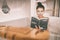 Woman reading book in warm bathtub taking a bath relaxing at home - pamper wellness Asian girl pampering skin care with