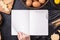 Woman is reading cookbook recipe of making Halloween cookies with baking ingredients, design concept of cooking class, top view,